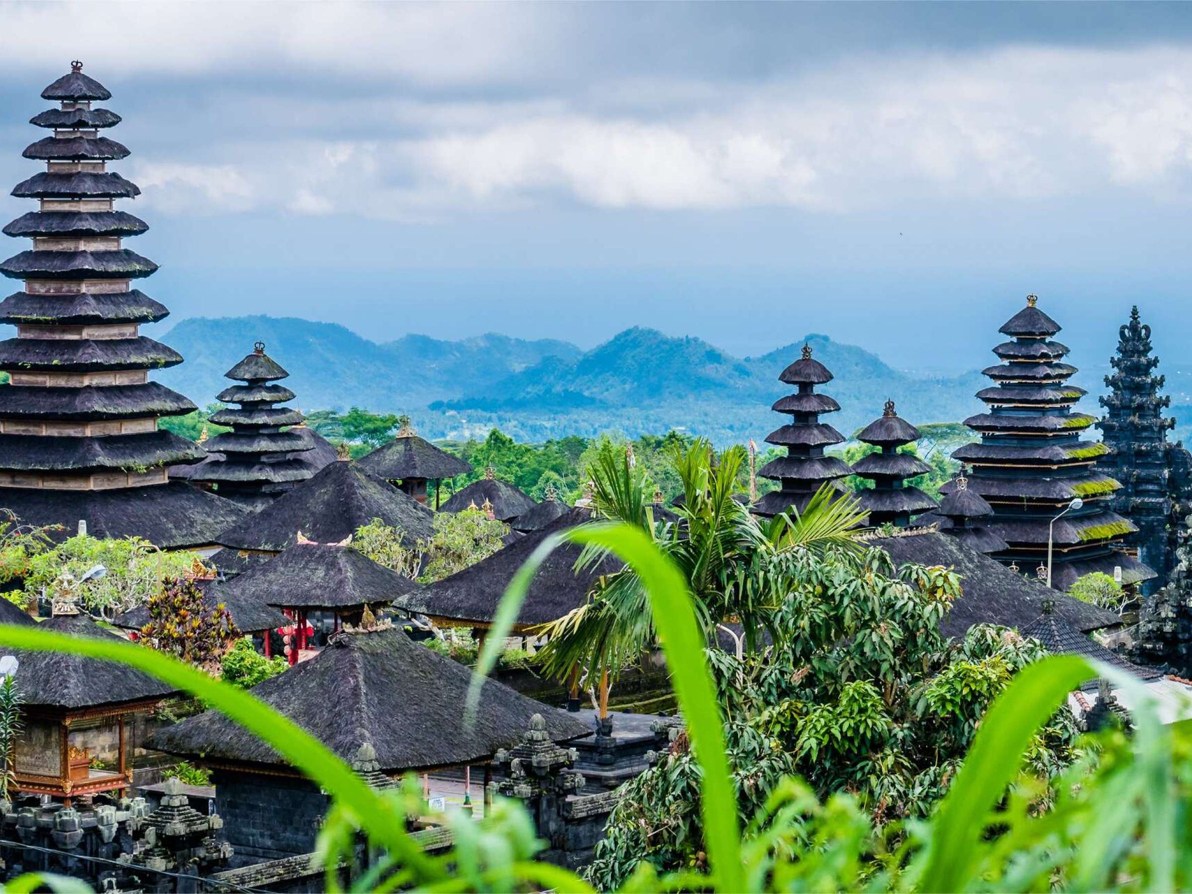 landscape picture of Balinese temples and greenery with mountains in the background